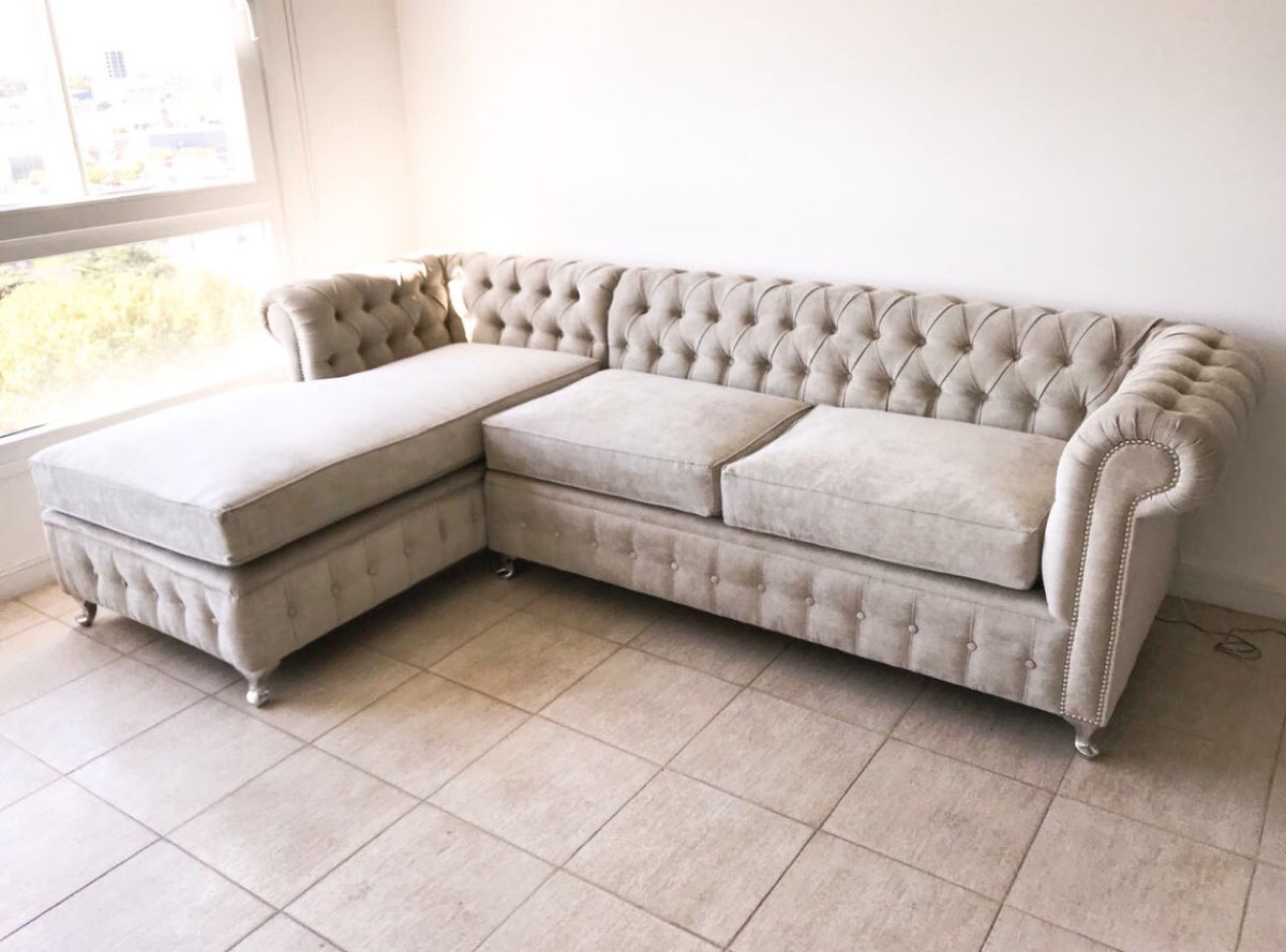 Esquinero Chesterfield beige con capitoné, tachas plateadas y chaise, junto a la ventana del living de Catalina