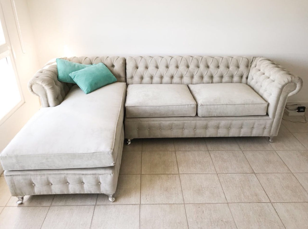 Vista de frente del Esquinero Chesterfield beige de Catalina, con almohadones turquesa sobre el chaise