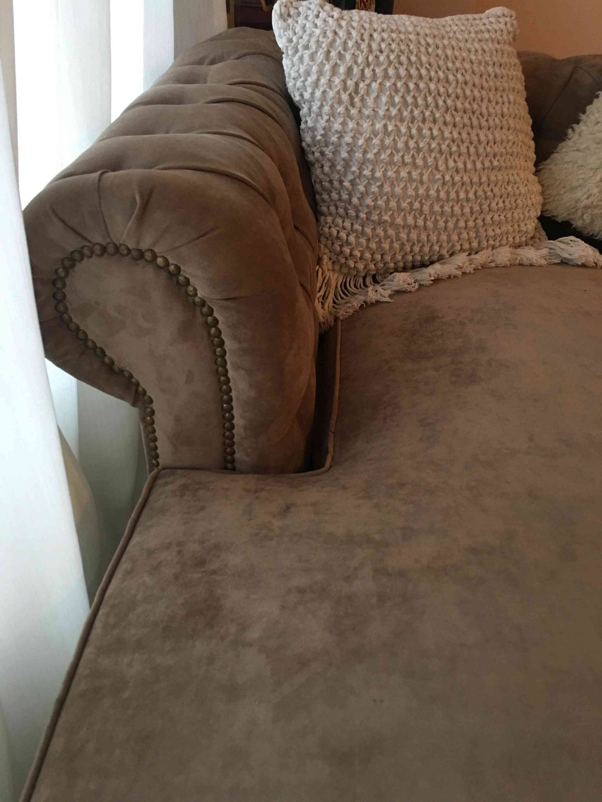 Detalle del brazo enrollado con tachas y el capitoné del Esquinero Chesterfield beige de Micaela