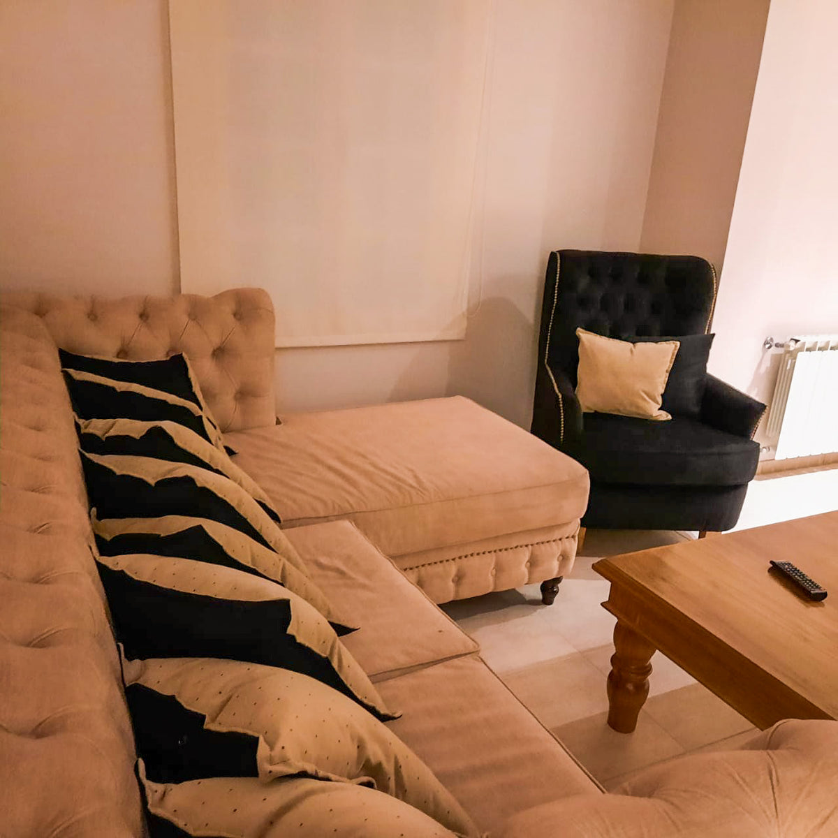 Esquinero Chesterfield beige con capitoné y chaise, con el Sillón Esmeralda negro al fondo, en el living de Rocío