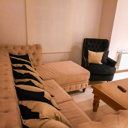 Esquinero Chesterfield beige con capitoné y chaise, con el Sillón Esmeralda negro al fondo, en el living de Rocío