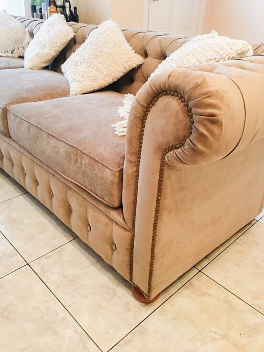 Detalle del apoyabrazos enrollado con capitoné del Esquinero Chesterfield rosa sobre piso cerámico