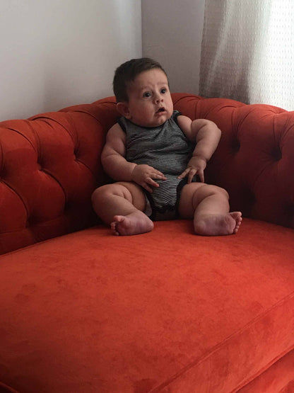 El bebé de Ludmila sentado en el Esquinero Chesterfield terracota, con el capitoné del respaldo detrás