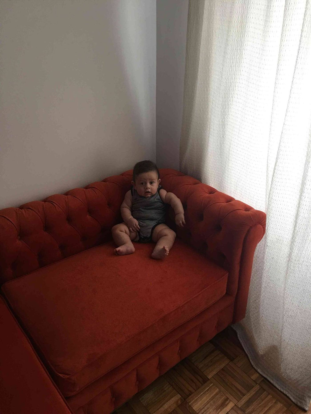 Esquinero Chesterfield en terciopelo terracota con capitoné y brazo enrollado, en el living de Ludmila en Adrogué