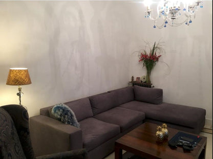 Vista general del living clásico de Lucrecia con el Esquinero Elton gris malva, el chandelier de cristal y la mesa ratona de madera
