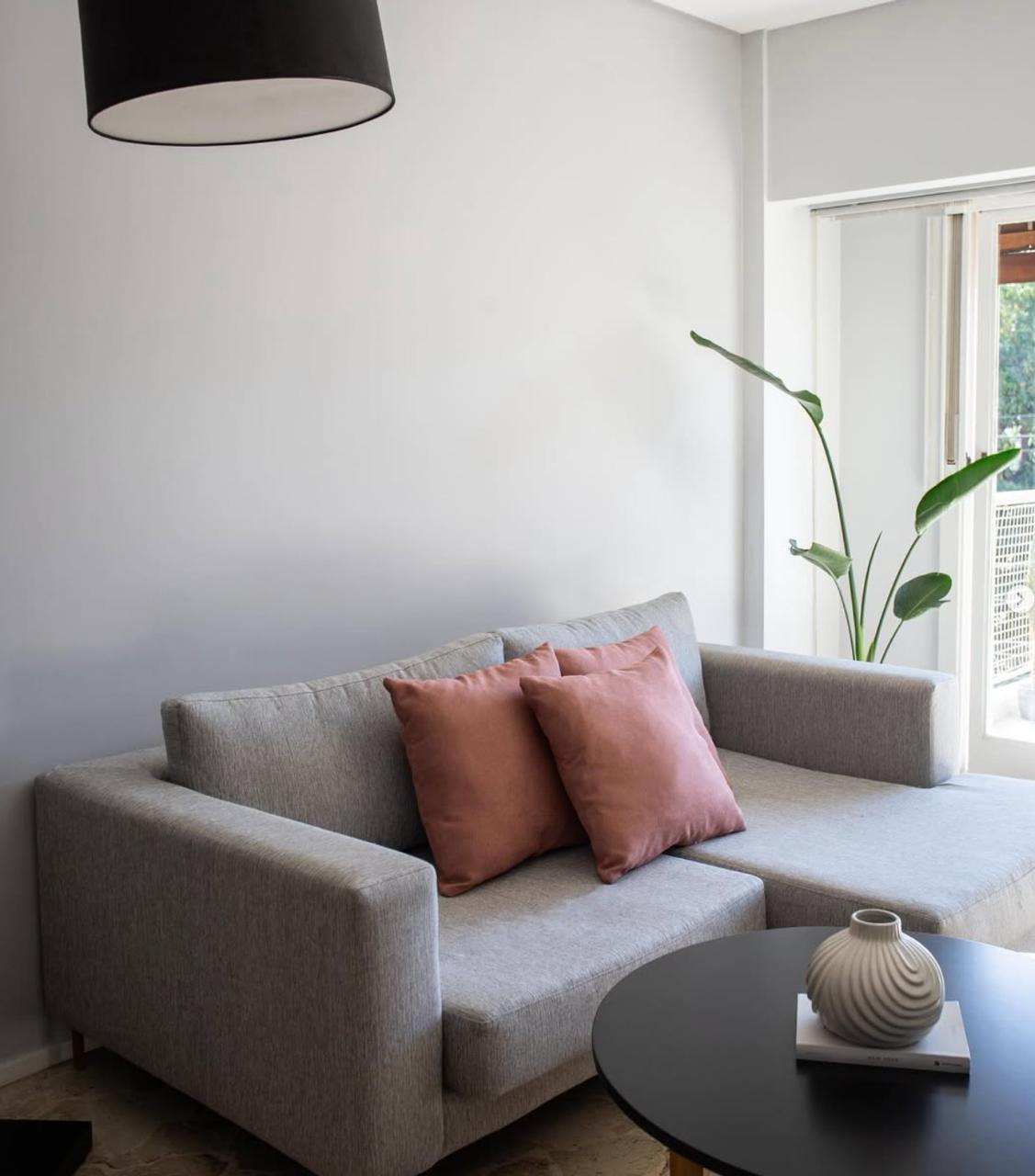 Esquinero Magnolia gris con chaise y almohadones terracota, en el living de un proyecto con WN Interiores