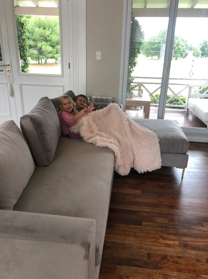 Esquinero Magnolia gris con chaise y patas doradas en el living de Débora, con sus dos hijos jugando bajo una manta