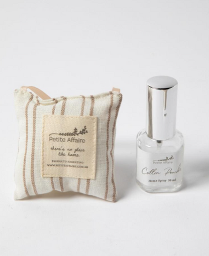 Almohadilla a rayas beige con etiqueta Petite Affaire junto al spray Cotton Powder de 30 ml