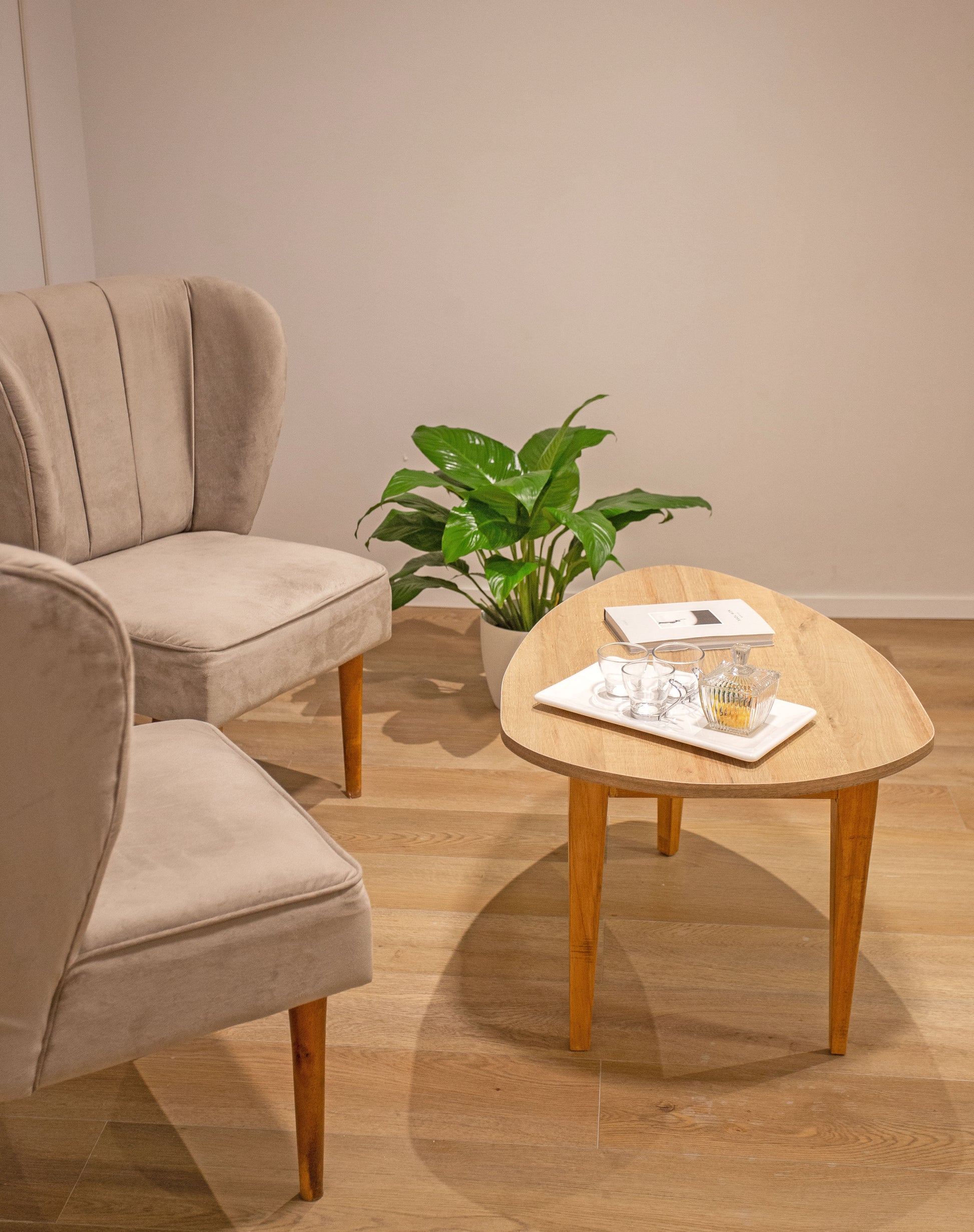 Dos butacas tapizadas en tela beige con respaldo alto y diseño con costuras verticales, apoyadas sobre patas de madera clara