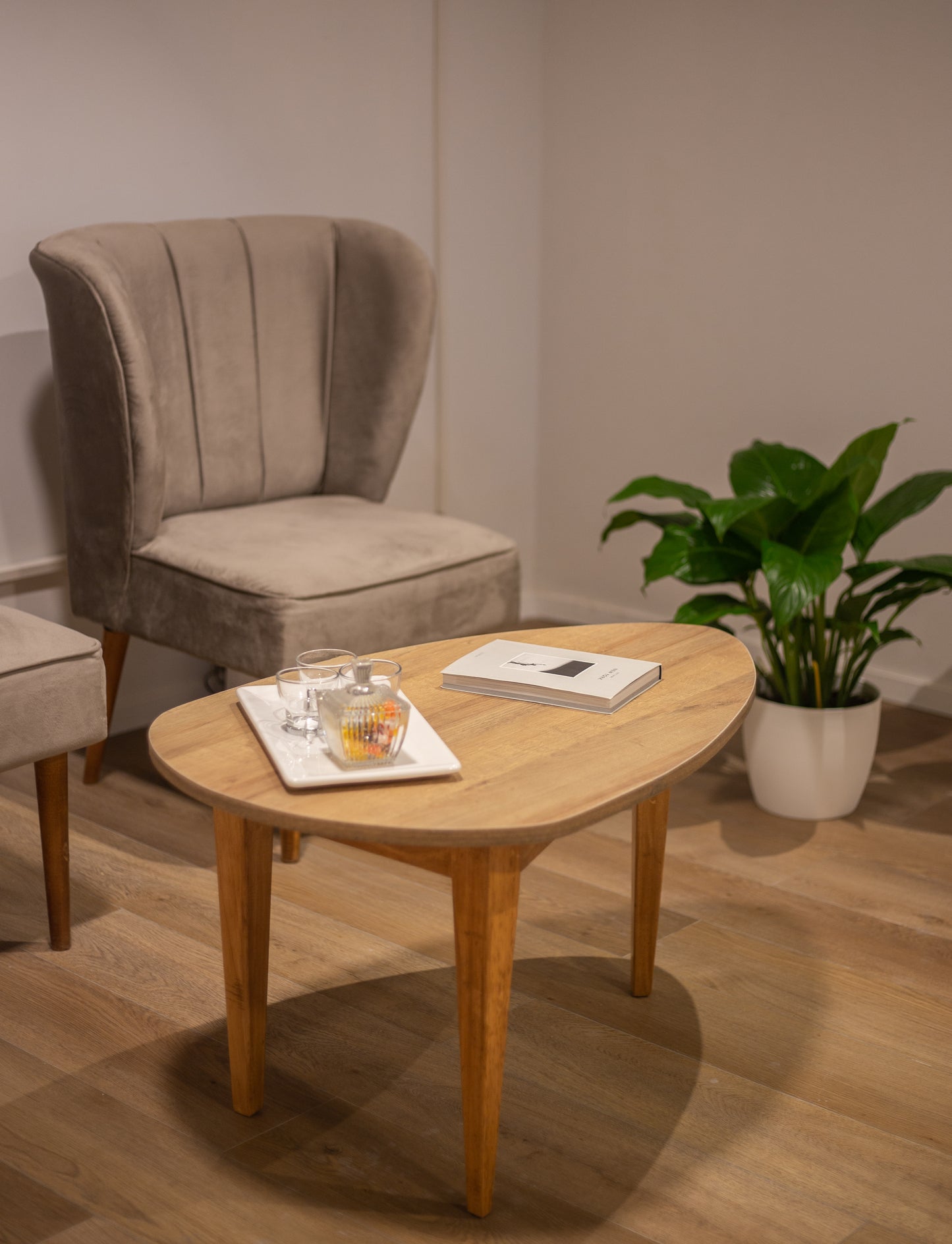 Dos butacas tapizadas en tela beige con respaldo alto y diseño con costuras verticales, apoyadas sobre patas de madera clara