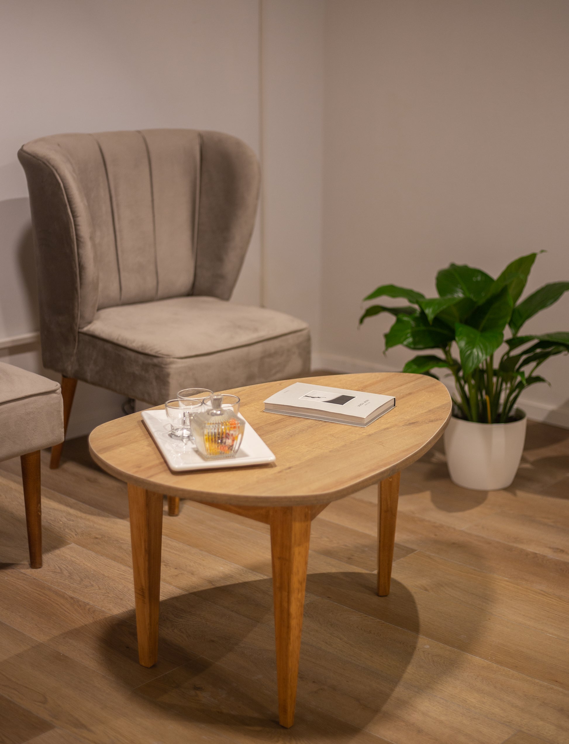 Dos butacas tapizadas en tela beige con respaldo alto y diseño con costuras verticales, apoyadas sobre patas de madera clara