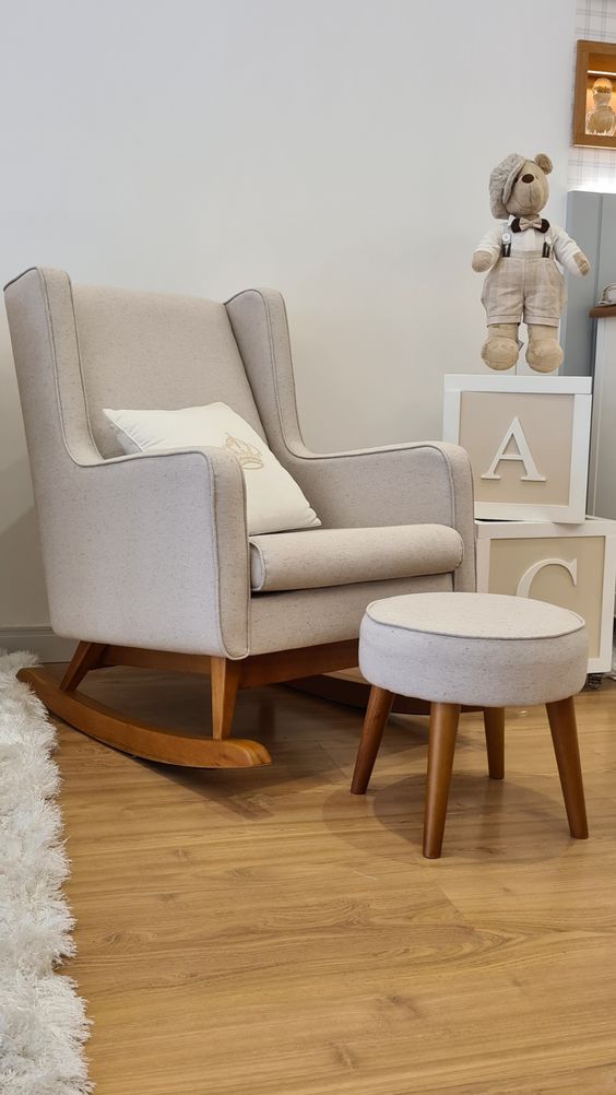 Mecedora Ciruelo en beige con un almohadón blanco, junto a un puff y cubos con letras en un cuarto infantil