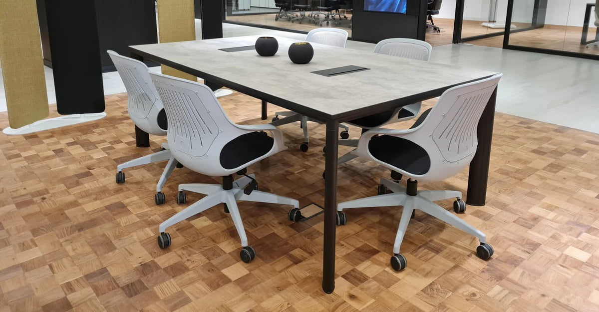 Mesa de reunión Equinox de Archivos Activos con tapa gris piedra, patas negras y sillas blancas