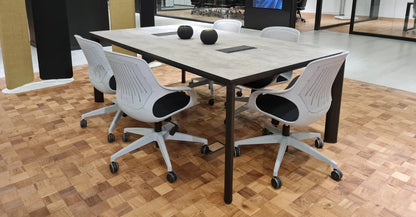 Mesa de reunión Equinox de Archivos Activos con tapa gris piedra, patas negras y sillas blancas