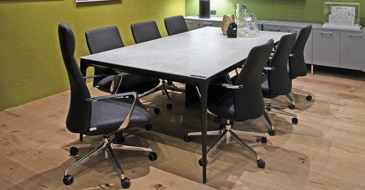 Mesa de reunión Eter de Archivos Activos con tapa gris, patas negras finas y sillas gerenciales negras