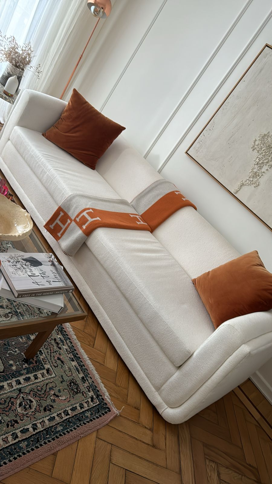 Sofá bouclé con líneas redondeadas y almohadones terracota, visto desde arriba en el living de Milagros Maylin
