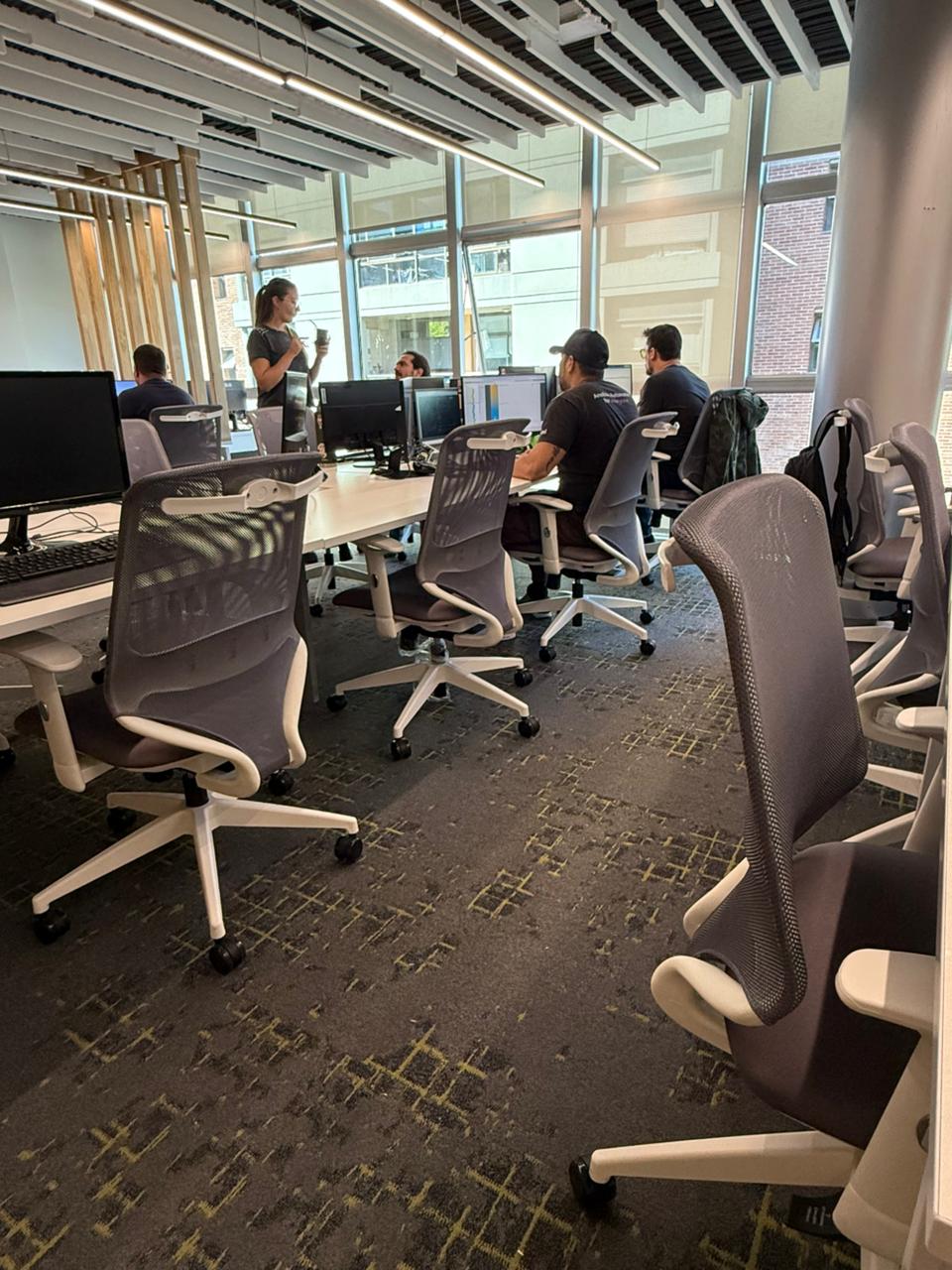 Equipo trabajando en escritorios compartidos con sillas Aston en One Cloud