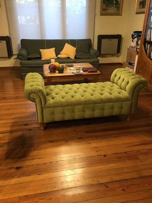 Banqueta Chesterfield capitoné en verde oliva con tachas y patas torneadas, en el living de parquet de Florencia