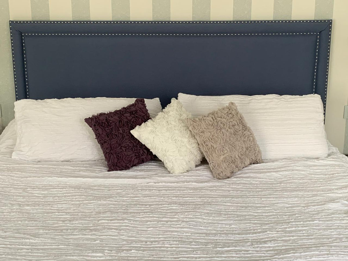 Respaldo de cama Grace en azul marino, con marco doble de tachas plateadas, tapizado a medida sin capitoné