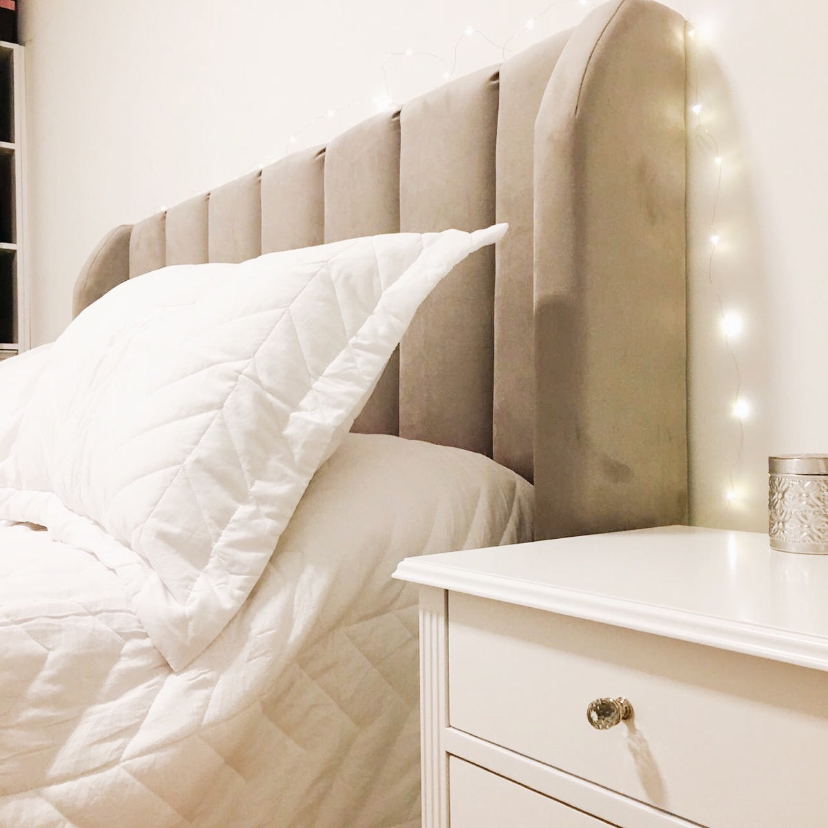 Perfil del Respaldo Alpes beige de Yamila junto a una mesa de luz blanca
