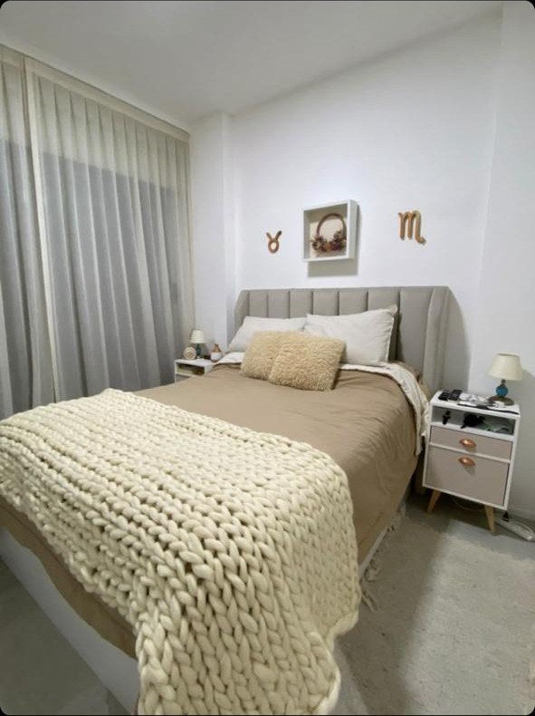 Dormitorio de Luli con el Respaldo Alpes gris, manta trenzada de lana y los cuadros de signos zodiacales