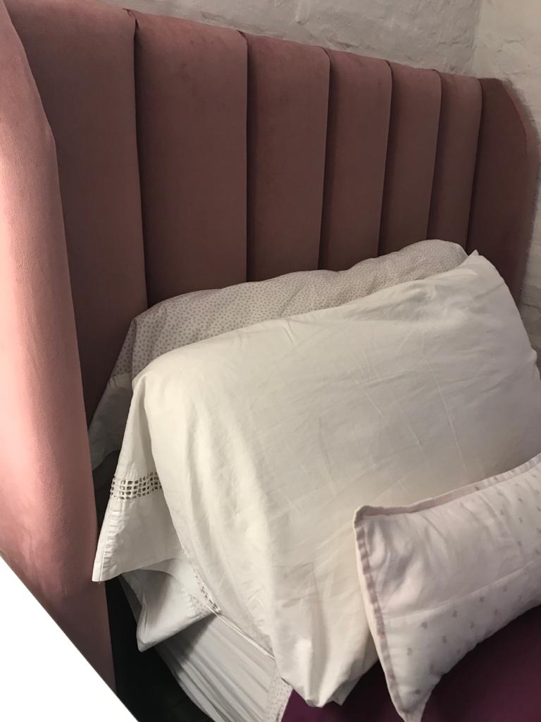 Respaldo Alpes rosa viejo con canales verticales y orejas, frente a la pared de ladrillo pintado del dormitorio de Emilia