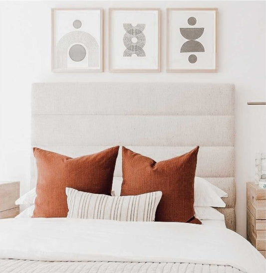Respaldo de Cama Agnes crudo, rectangular y con franjas horizontales, con almohadones terracota y tres cuadros arriba