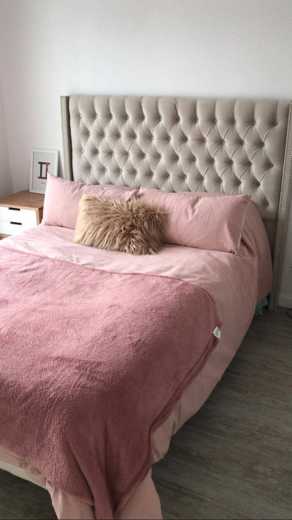Respaldo Emmy beige con capitoné profundo, aletas laterales y doble hilera de tachas plateadas, en el dormitorio de Renata con ropa de cama rosa