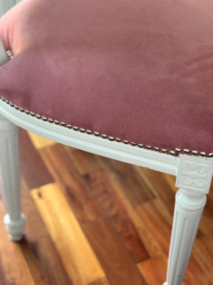 Detalle del asiento rosa con tachas de la silla blanca del dormitorio