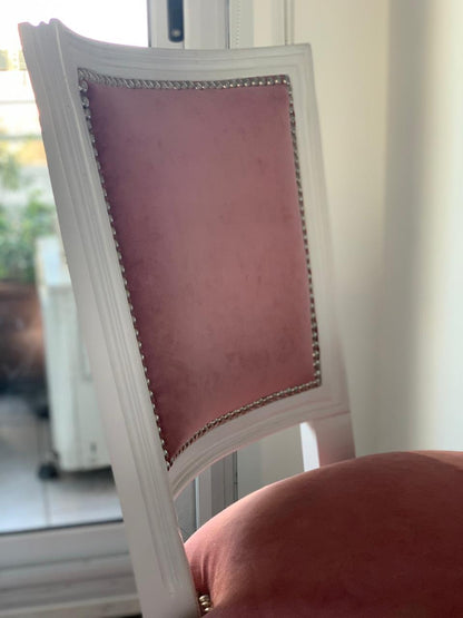 Detalle del respaldo de una silla blanca tapizada en rosa con tachas, en el dormitorio del Emmy