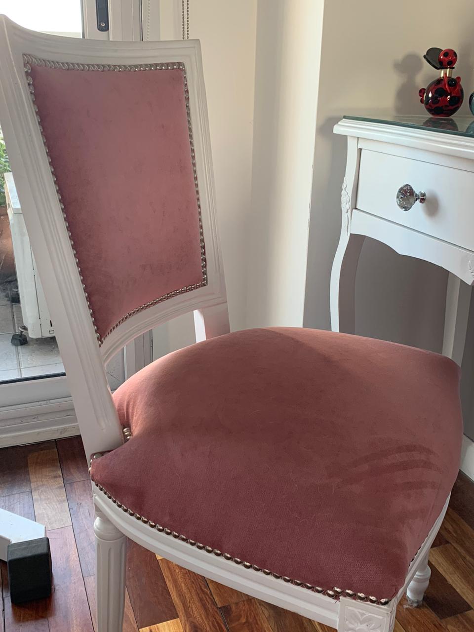 Silla blanca de estilo francés tapizada en rosa con tachas, junto al tocador