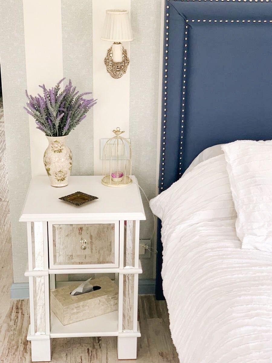 Detalle del marco de tachas plateadas del Respaldo Grace azul navy junto a la mesa de luz espejada de Patricia