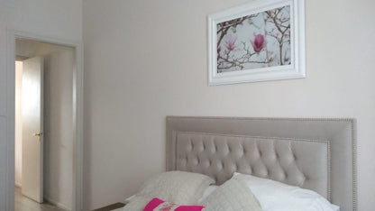 Vista general del Respaldo Grace beige con tachas plateadas bajo un cuadro de magnolias, en el dormitorio de Estefanía