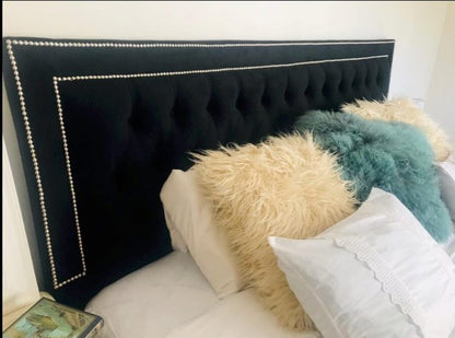 Detalle del Respaldo Grace negro con capitoné y doble marco de tachas plateadas, con almohadones de pelo claro y turquesa, en el dormitorio de Marisol
