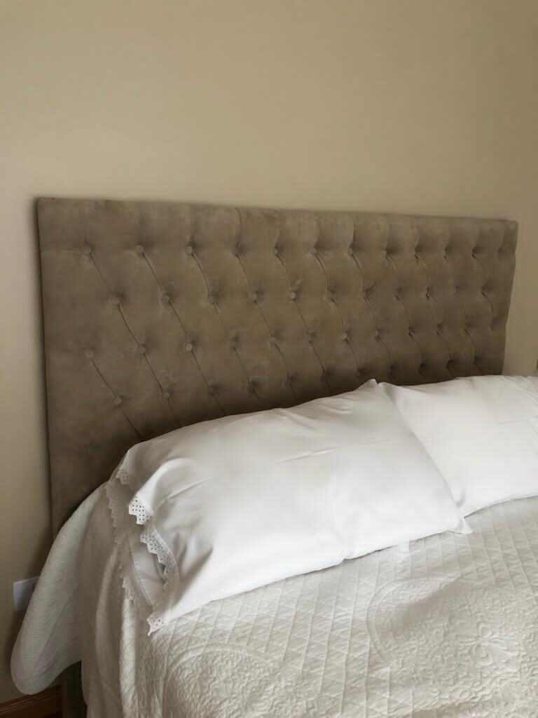 Respaldo Mily beige con capitoné de botones en toda la superficie y sin marco, detrás de una cama con ropa blanca en el dormitorio de Guillermina