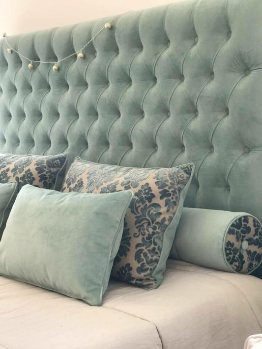 Respaldo Mily en terciopelo verde menta con capitoné en diamante, con almohadones al tono y de damasco azul, en el dormitorio de Araceli