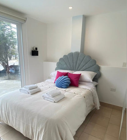 Respaldo de Cama Ostras celeste en forma de concha, con almohadones fucsia y azul, en el dormitorio de Fondo de Mar en Ushuaia