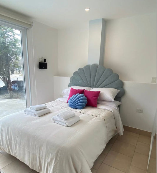 Respaldo de Cama Ostras celeste en forma de concha, con almohadones fucsia y azul, en el dormitorio de Fondo de Mar en Ushuaia