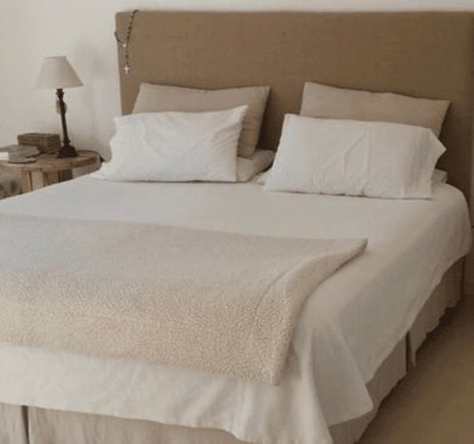 Respaldo Simply en taupe, liso y sin costuras, con ropa de cama blanca y una mesa de luz de madera rústica, en el dormitorio de Florencia en Rosario
