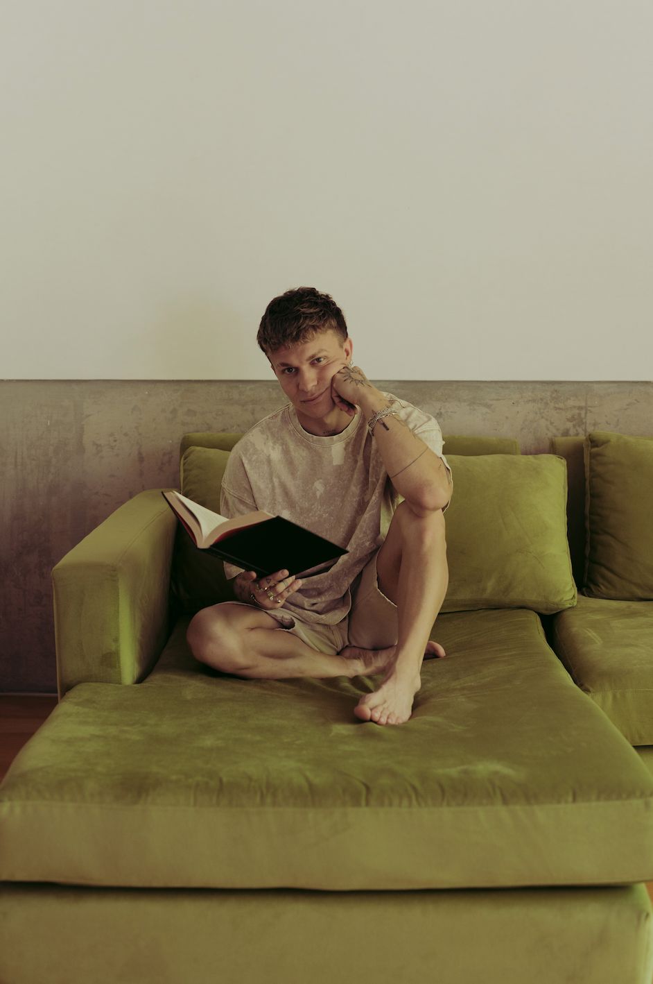 Santiago Colinet apoyado en los almohadones de su Sillón Esquinero Richard verde, leyendo