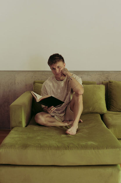 Santiago Colinet apoyado en los almohadones de su Sillón Esquinero Richard verde, leyendo