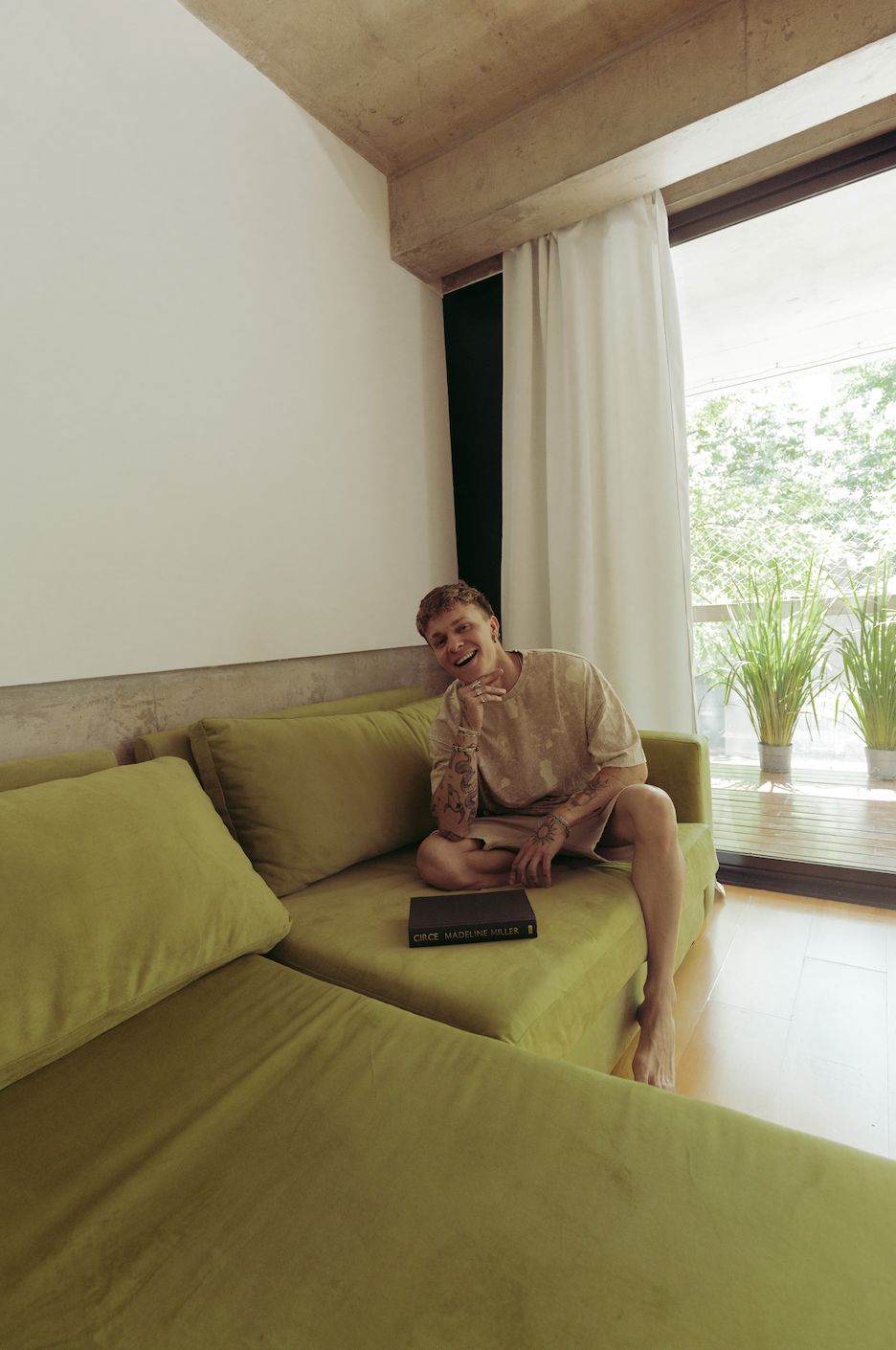 Santiago Colinet posando con un libro en su Sillón Esquinero Richard verde, junto a la ventana