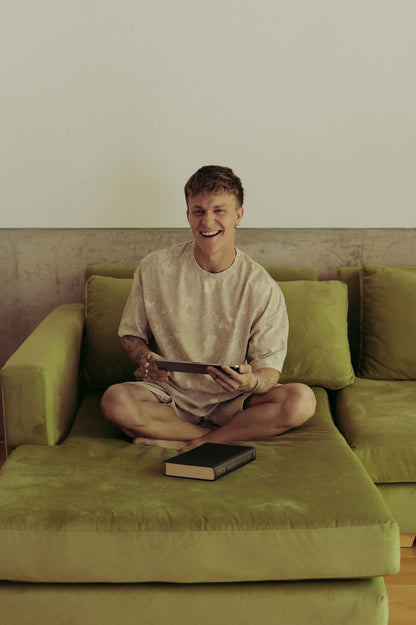 Santiago Colinet sonriendo, sentado en el centro de su Sillón Esquinero Richard verde