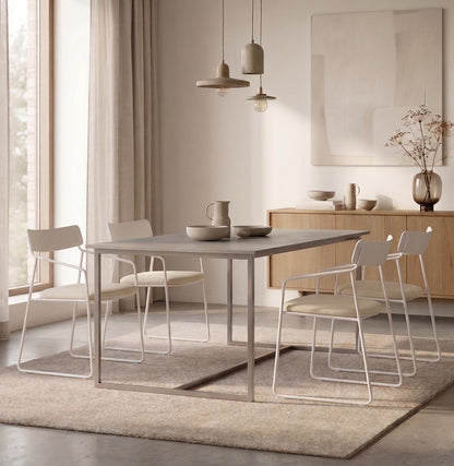 Cuatro Sillas Cubo blancas alrededor de una mesa de comedor gris, junto a un aparador de madera