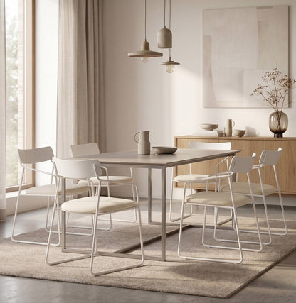 Seis Sillas Cubo blancas con asiento crema alrededor de una mesa gris, sobre una alfombra clara