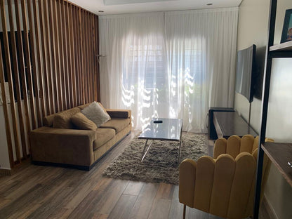 Living de Yamila con el Sillón Angie mostaza frente a un sofá marrón, una pared de varillas de madera y cortinas blancas