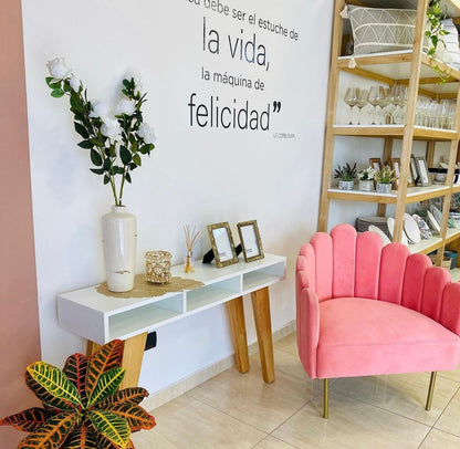 Sillón Angie en pana rosa con patas doradas junto a una consola blanca, en el local De Casas de Firmat, Santa Fe
