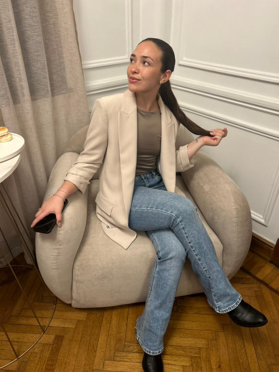 Clienta en el Sillón Cabsha bouclé junto a la boiserie blanca de la recepción de The Club
