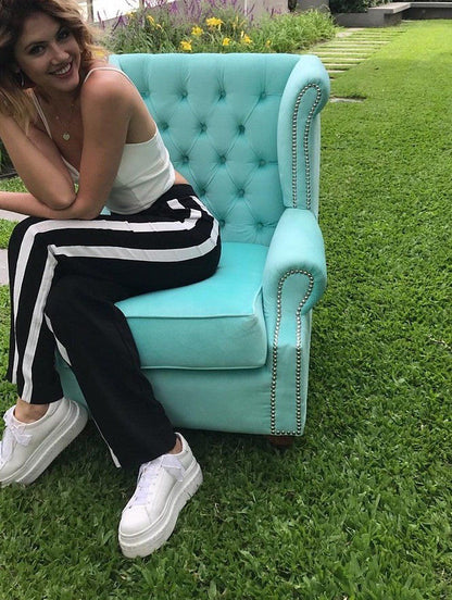 Stephanie Demner sentada en su Sillón Elepant celeste, color a pedido, con tachas plateadas