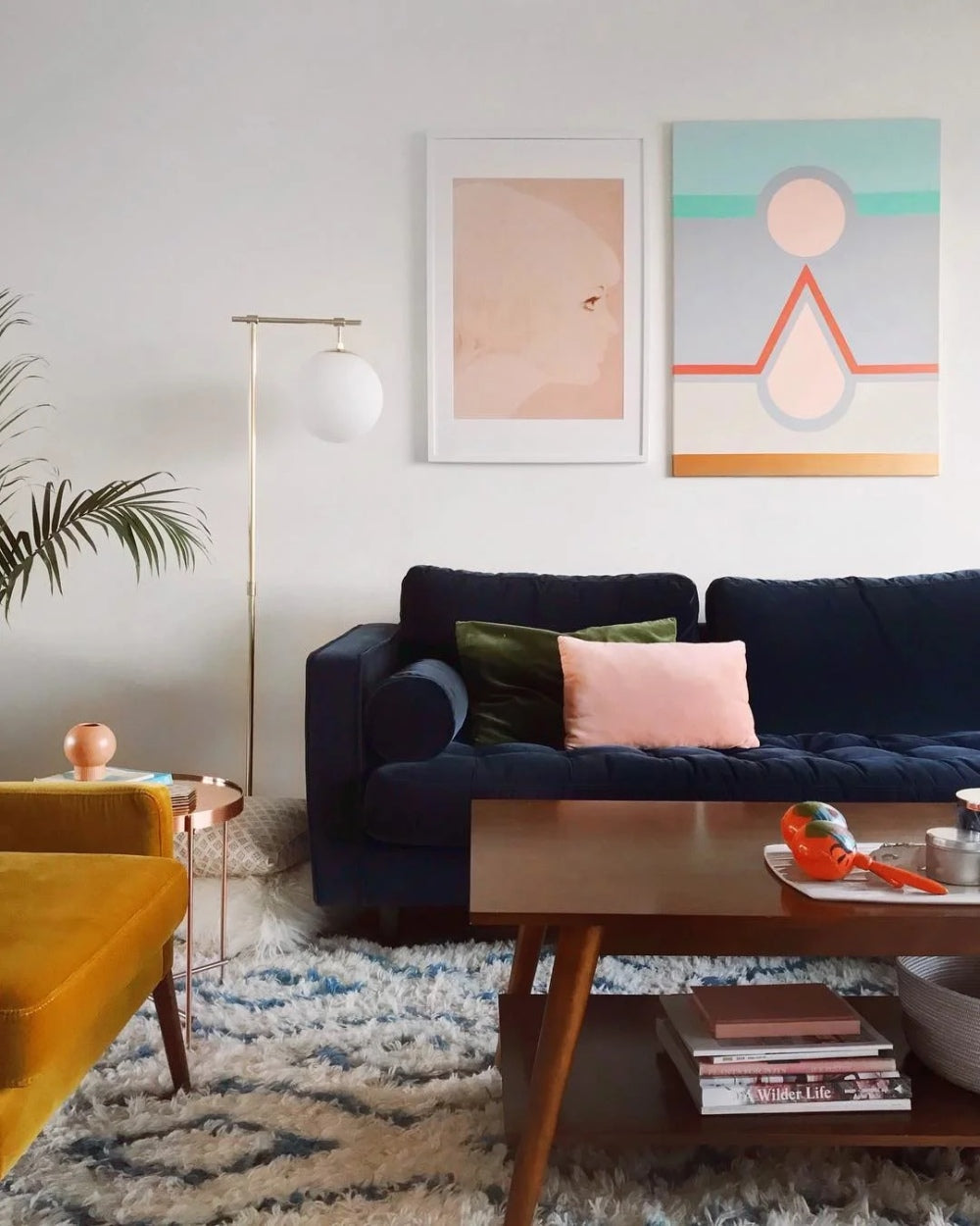 Sillón esquinero Bambú en azul con almohadones rosa y verde, junto a una butaca mostaza